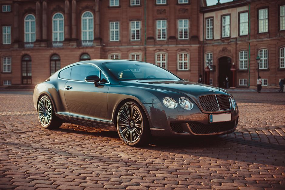 Elegant Bentley Continental GT on cobblestone street in historic Copenhagen during daytime.